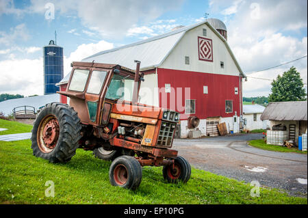 Vintage trattore rosso vicino al red e pitturato di bianco fienile vicino a Garrett County, Maryland, Stati Uniti d'America Foto Stock