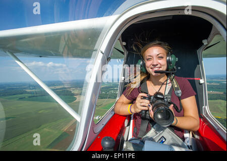 Donna sorridente fotografo tenere la fotocamera in piccolo aeroplano mentre airborne, in Ridgley, Maryland, Stati Uniti d'America Foto Stock