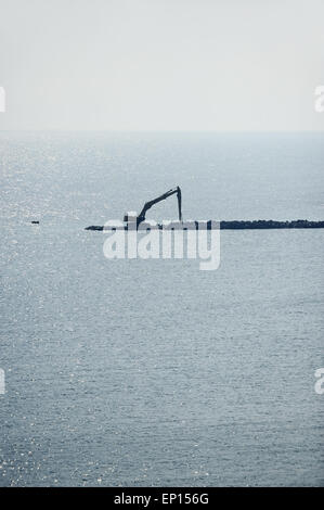 Macchina industriale la costruzione di una diga in mare Foto Stock