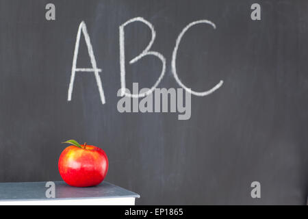 Pila di libri con una mela rossa e una lavagna con ABC scritto su di esso Foto Stock