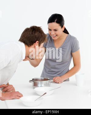 Uomo bello assaggiando una salsa fatta con la sua ragazza Foto Stock