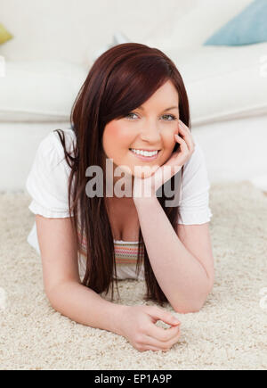 Felice i capelli rossi ponendo femmina mentre giaceva su un tappeto Foto Stock