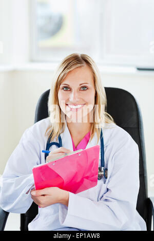 Ritratto di un medico bello scrivere le note utilizzando una clipboard Foto Stock