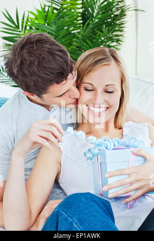 Attento uomo baciando la sua fidanzata dopo di lei una presente sia sdraiato sul lettino Foto Stock