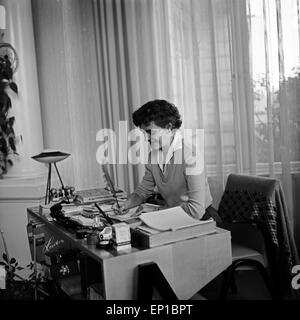 Eine Frau sitzt am Schreibtisch und schreibt mit einer Feder, Deutschland 1950er Jahre. Una donna seduta alla sua scrivania e la scrittura Foto Stock