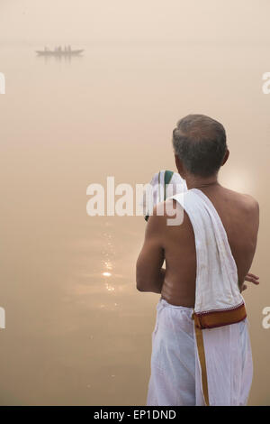 Uomo che prega al mattino sulla riva del fiume Gange. Foto Stock