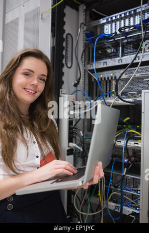 Donna felicemente utilizzando notebook per lavorare su server Foto Stock