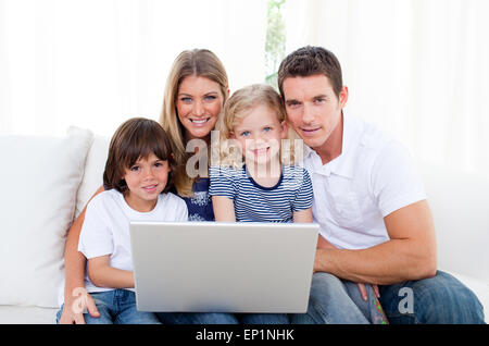 Ritratto di una gioiosa famiglia utilizzando un laptop seduto sul divano Foto Stock