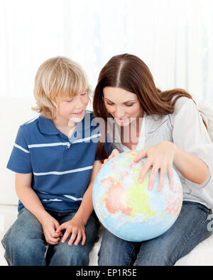 Interessati bambino guardando un globo terrestre con sua madre Foto Stock