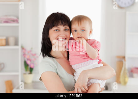 Bella donna mentre tiene il suo bambino in braccio mentre in piedi Foto Stock