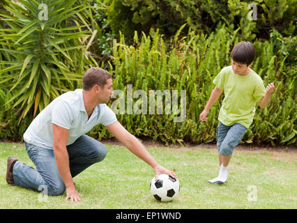 Figlio giocando a calcio con suo padre Foto Stock