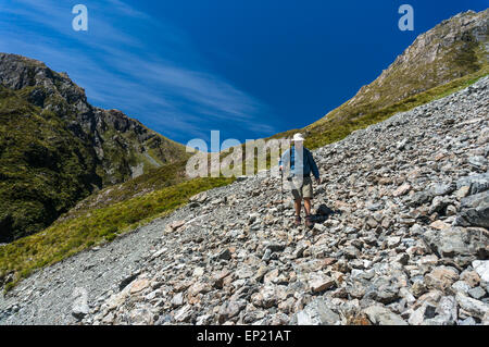 Uomo che cammina attraverso un ghiaione in Arthur's Pass National Park, Nuova Zelanda Foto Stock