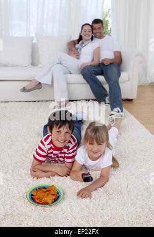 Dei bambini felici di guardare la televisione sul pavimento in soggiorno Foto Stock