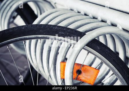 Frammento di un parcheggiato la ruota di bicicletta con arancio brillante riflettore, vintage foto dai toni Foto Stock