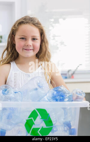 Bambina portando scatola piena di bottiglie in plastica Foto Stock