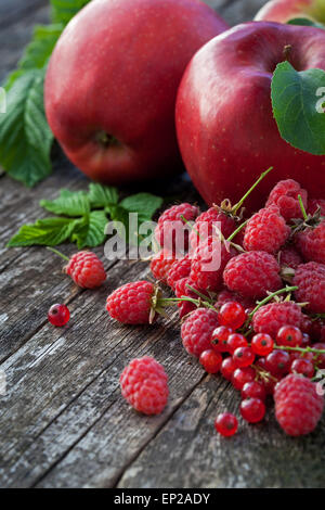 Ribes rosso, rasberry e mele rosse sul vecchio tavolo in legno, mix di colore rosso vitamine concept Foto Stock