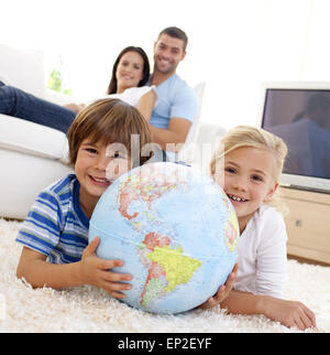 Bambini che giocano con un globo terrestre a casa Foto Stock