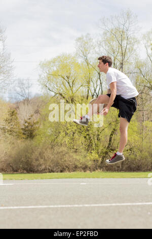 Giovane uomo che fa del basket trick shots come egli salta attraverso l'aria Foto Stock