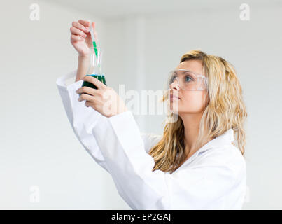 Donna in lapcoat guardando i prodotti chimici Foto Stock