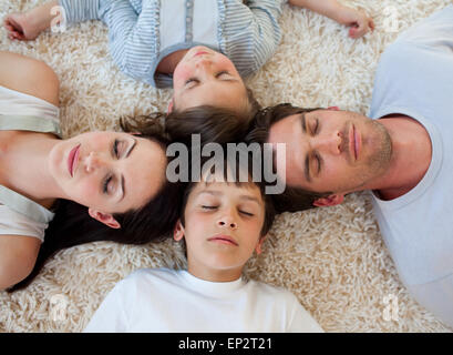 Famiglia dormire sul pavimento con teste insieme Foto Stock