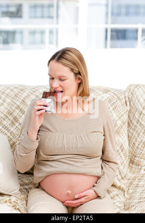 Gioiosa donna incinta gustano cioccolato durante il riposo Foto Stock