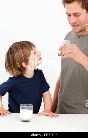 Little Boy guardando suo padre bere latte Foto Stock