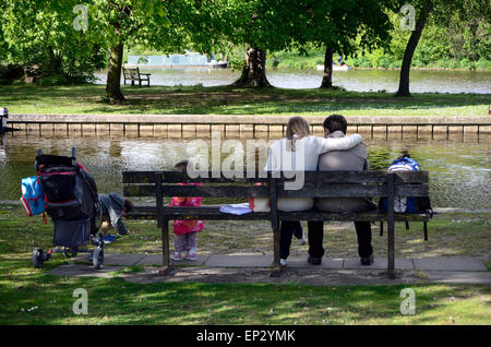 Una famiglia giovane seduto su una panchina dal fiume Tamigi in Windsor, Berkshire Foto Stock