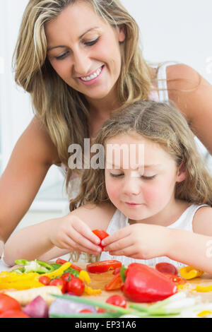 Madre guardando la figlia a preparare verdura Foto Stock