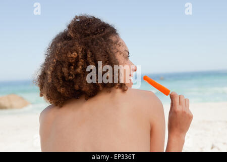 Sorridente donna attraente di trattenimento di un arancione per lecca-lecca di ghiaccio Foto Stock