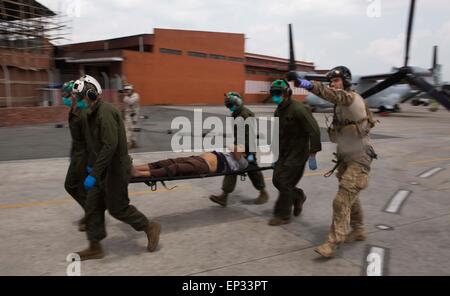 Kathmandu, Nepal. 13 Maggio, 2015. Un U.S. Air Force pararescueman dirige Marines che trasportano un uomo Nepalese ad una area di triage a l'aeroporto internazionale di Tribhuvan Maggio 12, 2015 a Kathmandu, Nepal. Un 7.3 grandezza aftershock terremoto ha colpito il regno a seguito del 7.8 terremoto di magnitudine su Aprile 25th. Foto Stock