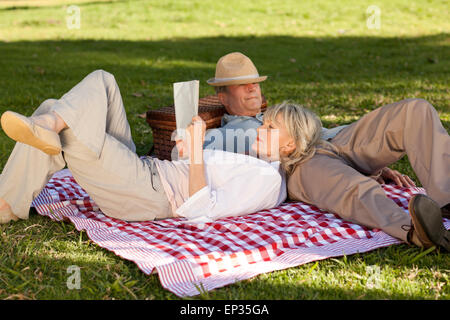 Donna lettura mentre il marito sta dormendo nel parco Foto Stock