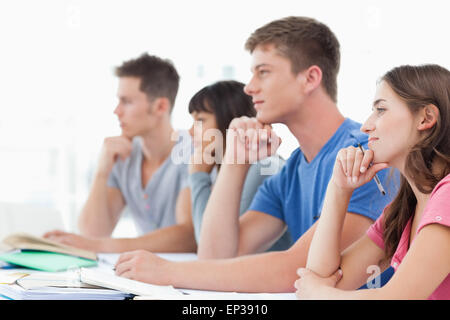 Vista laterale di quattro studenti con le mani sul loro pensiero i menti Foto Stock