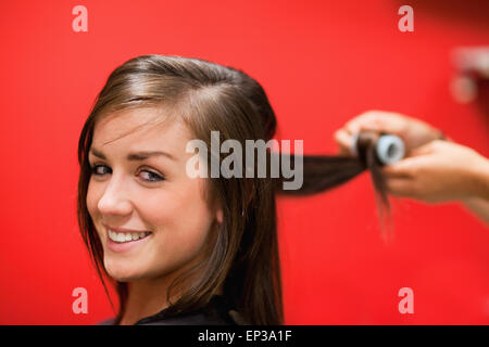 Donna sorridente con i suoi capelli avvolti Foto Stock