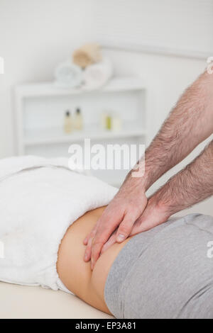 Donna sdraiata mentre un fisioterapista di massing il suo indietro Foto Stock