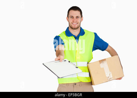 Sorridente giovane uomo di consegna con pacco chiedendo per la firma Foto Stock
