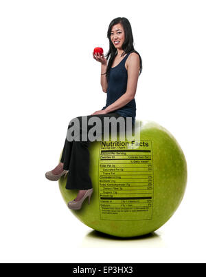 Asian donna seduta su Red Delicious Apple con etichetta nutrizionale Foto Stock