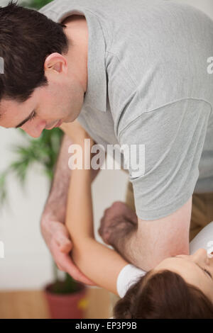 Grave osteopata ponendo il suo gomito della spalla di un paziente Foto Stock