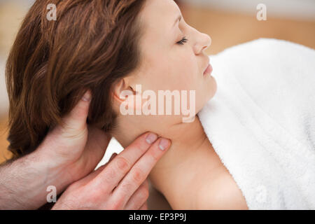 Terapista massaggiando il collo della donna tenendo la testa Foto Stock