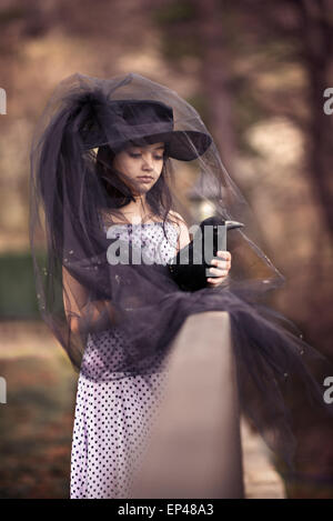 Ragazza in un velo nero tenendo un farcite black bird Foto Stock