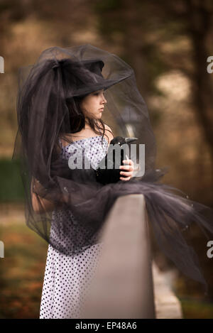 Ragazza in un velo nero tenendo un farcite black bird Foto Stock