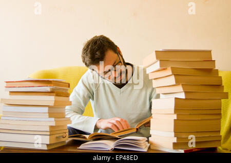 Uomo di studio con una pila di libri di fronte a lui Foto Stock