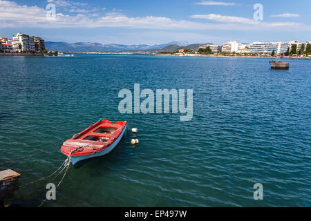 Barca legato al piccolo porto di CHALKIDA, EUBEA, GRECIA contro un cielo nuvoloso con la città di edifici in background Foto Stock