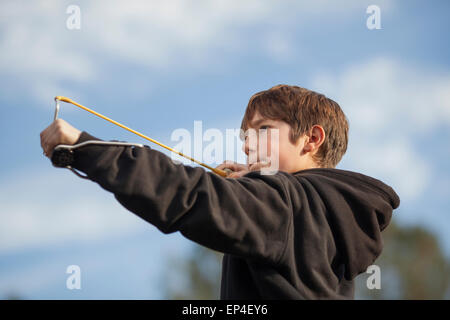 Un ragazzo puntando una slingshot all'esterno. Foto Stock