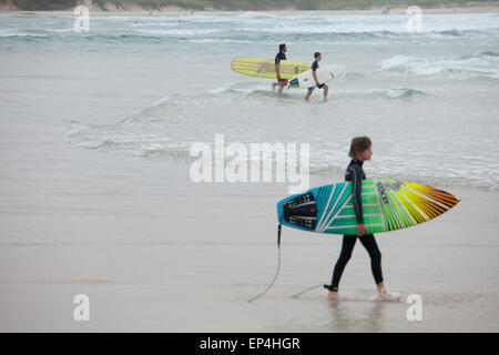 I surfisti a piedi fuori ad un surfbreak nella loro città natale di Byron Bay, Australia. Foto Stock