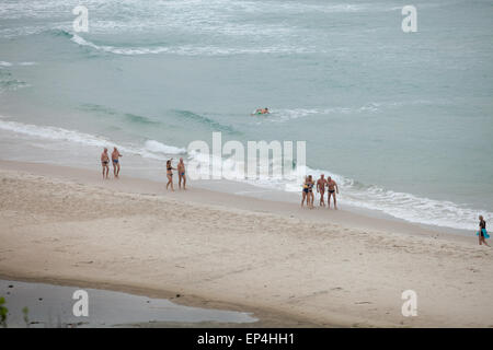 Forte nuotatori a piedi giù per la spiaggia dopo la loro lunga nuotata nell'oceano in Byron Bay, Australia. Foto Stock