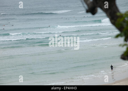 Un surfista voce fuori in un affollato surf spot in Byron Bay, Australia. Foto Stock