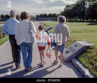 Giugno 25, 1989 - Leningrado (St. Petersburg, Russia - un gruppo di famiglia a piedi verso il basso il percorso al Piskaryovskoye Memorial Cemetery di Leningrado (presente giorno San Pietroburgo) passato il leggermente sollevata tumuli segnati da anno, che sono alcuni dei 186 tombe di massa dove mezzo milione di persone, tra cui 420.000 civili, e 50.000 soldati, sono sepolti dopo perire durante l epica di 900 giorni di assedio da parte dei nazisti durante la seconda guerra mondiale. Molti San Pietroburgo famiglie provengono al cimitero ogni anno portando fiori e rendere omaggio alla città di difensori e i membri della propria famiglia, che morì durante l'assedio. Foto Stock