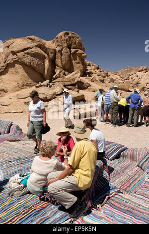 L'Egitto, il Sinai beduini Desert Camp, turisti sat su tappeti di mangiare pane piatto Foto Stock