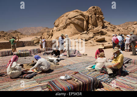 L'Egitto, il Sinai beduini Desert Camp, turisti sat su tappeti di mangiare pane piatto Foto Stock