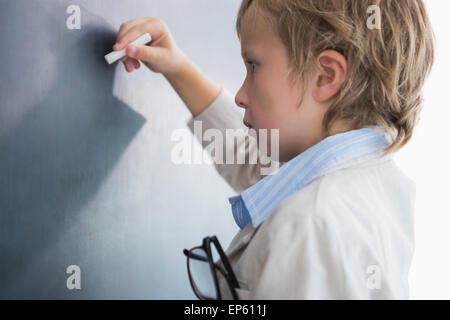 Ragazzo vestito come insegnante e scrive sulla lavagna nera Foto Stock